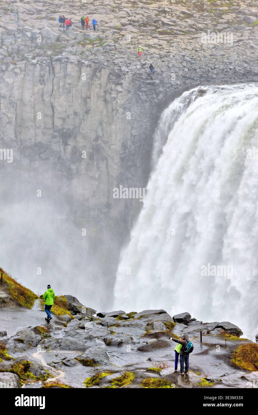 I visitatori si trovano vicino al bordo della cascata Dettifoss in Islanda, osservando i potenti flussi d'acqua e la nebbia che si innalzano dalle cascate. Foto Stock