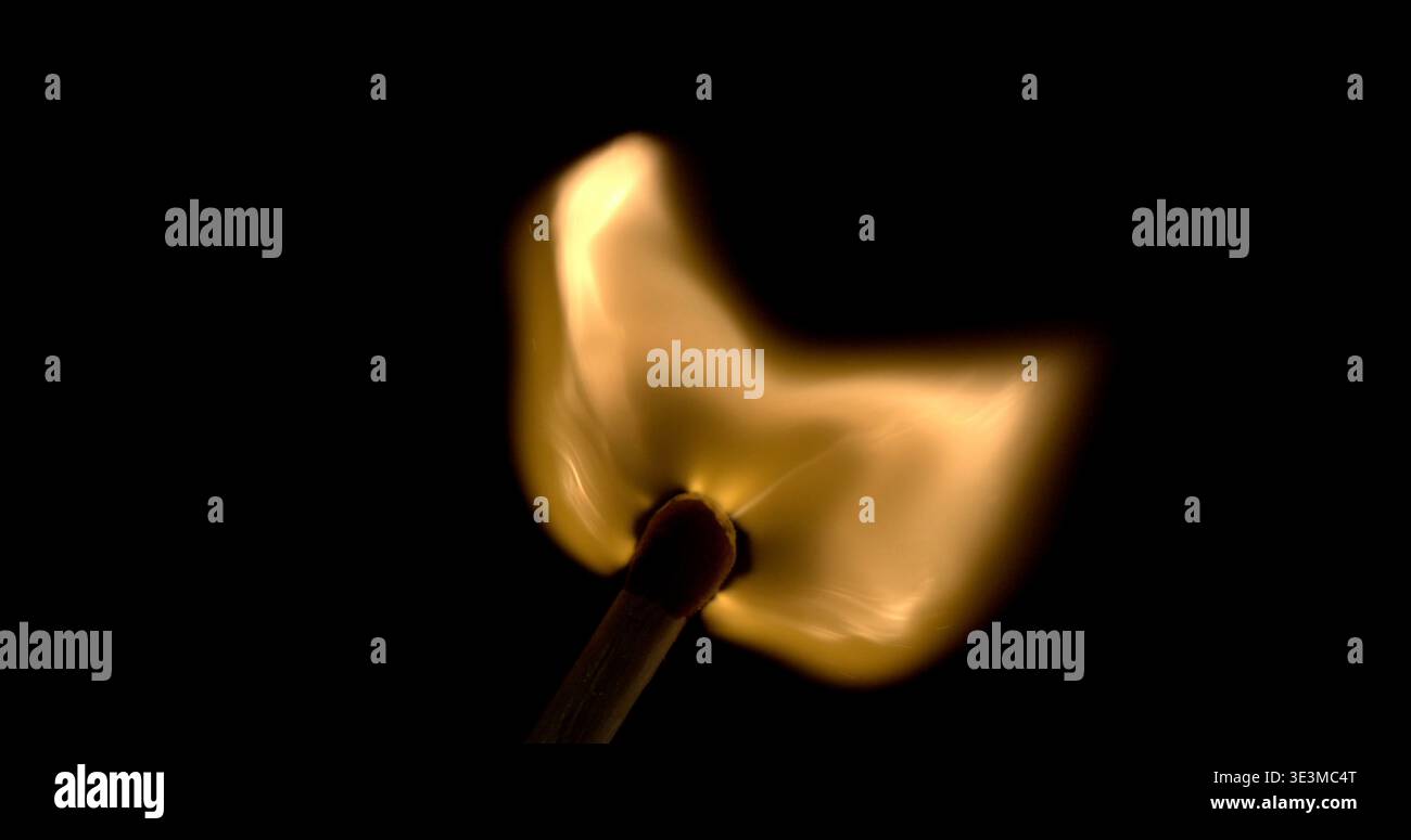 Fiamma accesa su un fiammifero tenuto in un ambiente buio con fumo che sale nell'aria Foto Stock