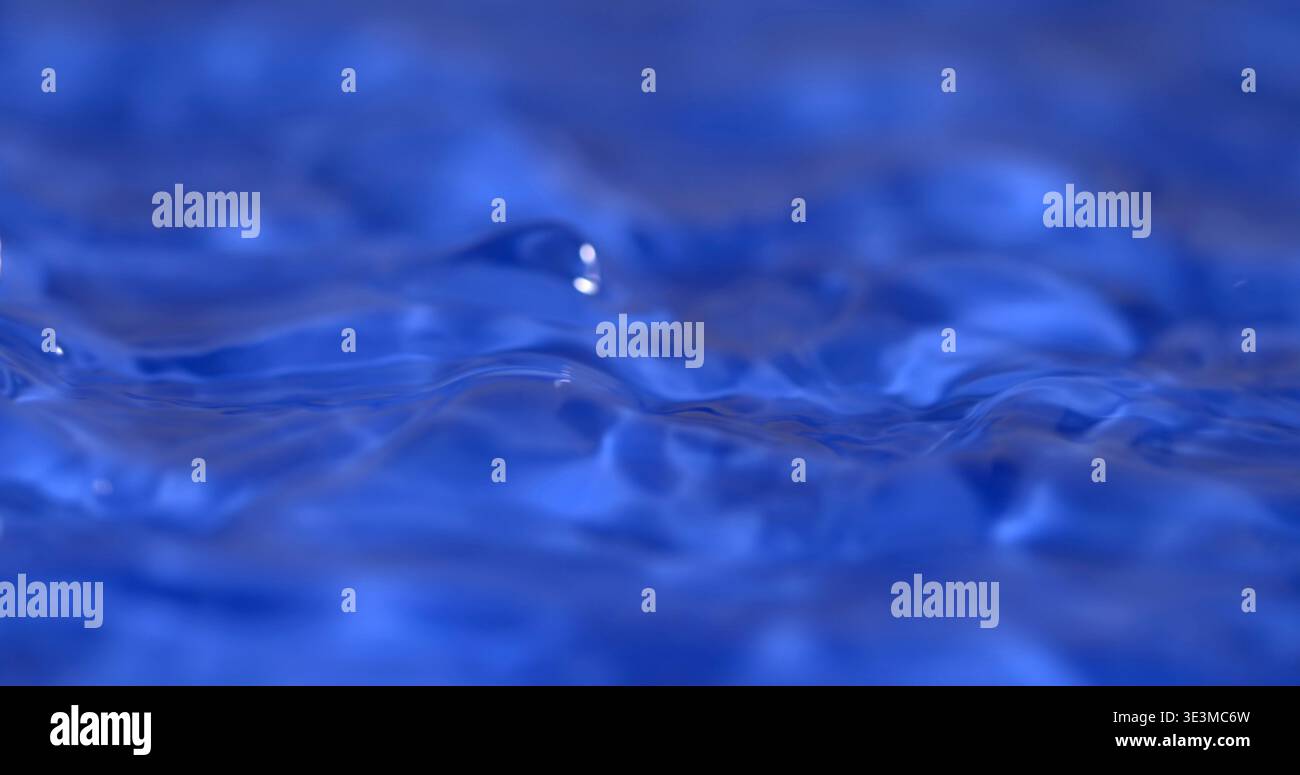 L'acqua scorre dolcemente in blu limpido, creando onde e increspature in un ambiente tranquillo sotto la luce intensa a mezzogiorno Foto Stock