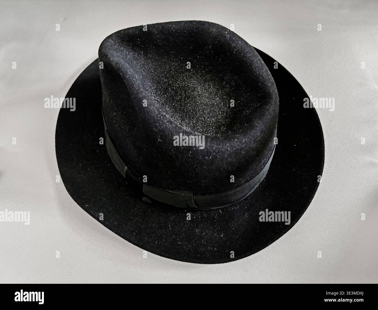 Un cappello di feltro nero poggia su una sedia bianca in una sinagoga a Singapore. Foto Stock