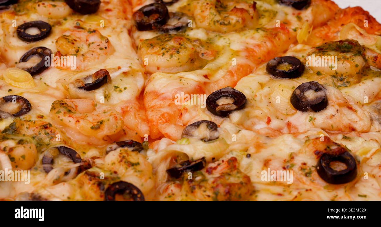 Pizza con gamberi e olive servita su un piatto con formaggio e peperoni verdi per pranzo Foto Stock