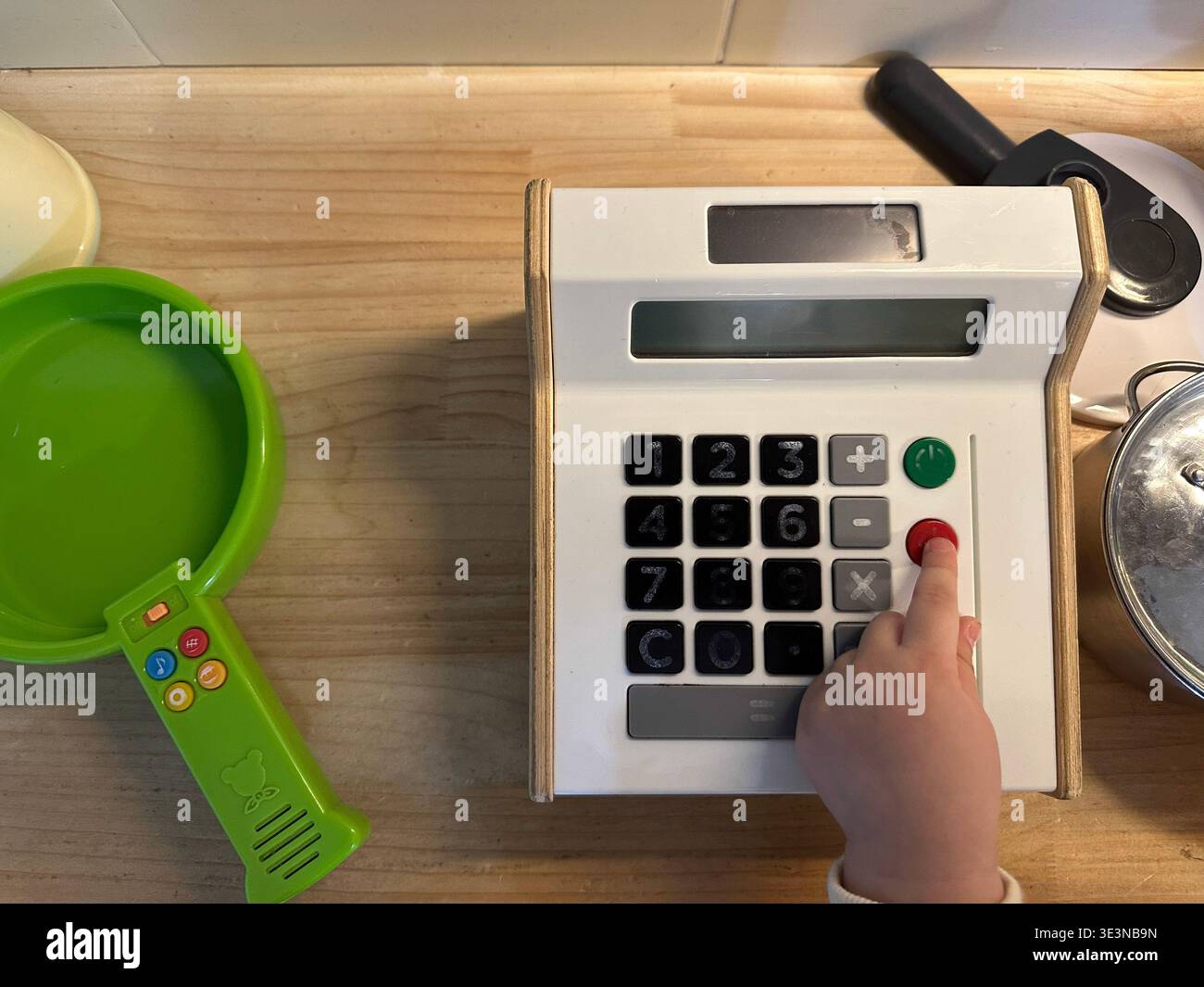 Primo piano di un bambino che preme i pulsanti di un registratore di cassa giocattolo. Gioco educativo per imparare matematica, conteggio e capacità finanziarie Foto Stock