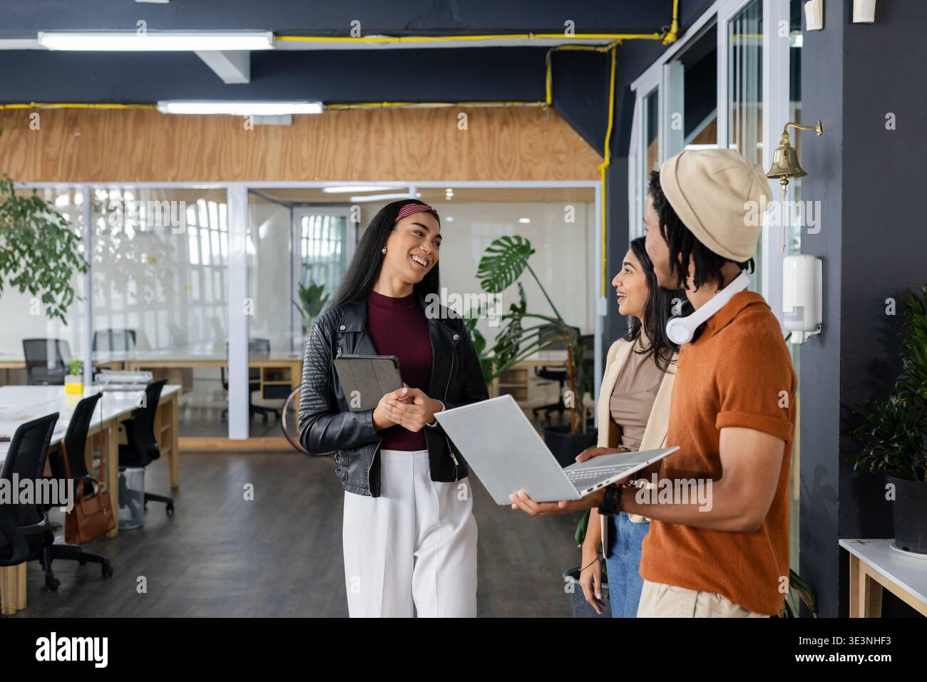 Diversi colleghi che chiacchierano vicino al servizio di assistenza e dispenser di igienizzatore con computer portatile in un ufficio moderno Foto Stock