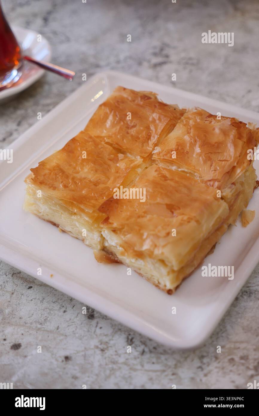 borek turco appena sfornato servito con tè in un ambiente da caffe' Foto Stock