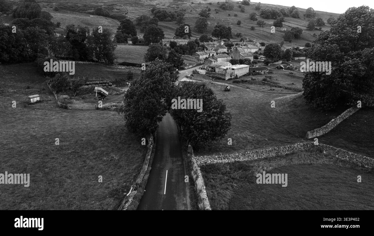 Vista aerea in bianco e nero della strada rurale che conduce al piccolo villaggio tradizionale di Swaledale Foto Stock