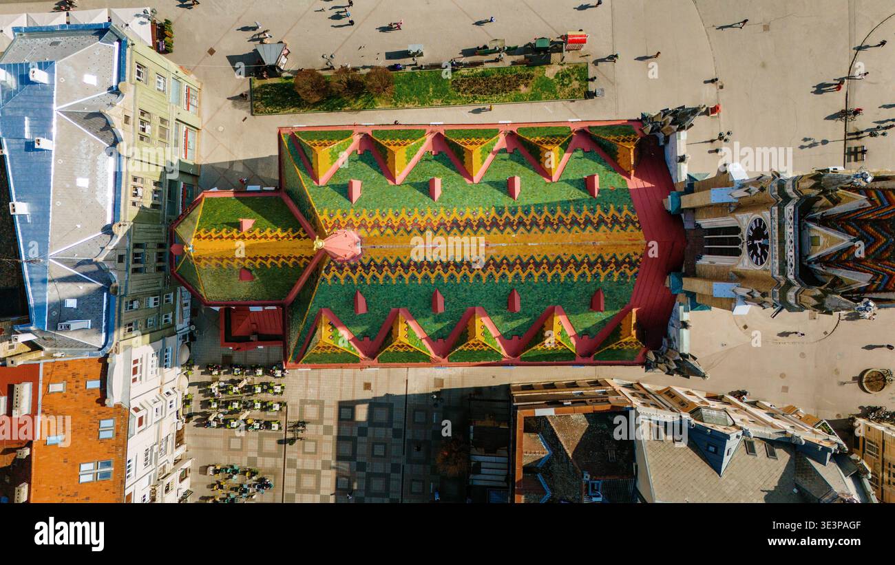 Vista aerea del vivace tetto a motivi geometrici della chiesa di Mattia, un arazzo di verde, giallo e rosso, che si erge orgogliosamente, Сад, Vojvodina, Serbia. Foto Stock
