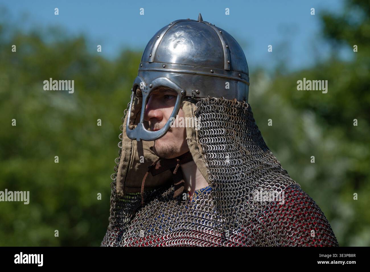 SHEVELEVO, RUSSIA - 18 LUGLIO 2025: Un giovane guerriero dell'alto Medioevo in un casco normanno e posta a catena in una giornata di sole. Epico festival della costa Foto Stock