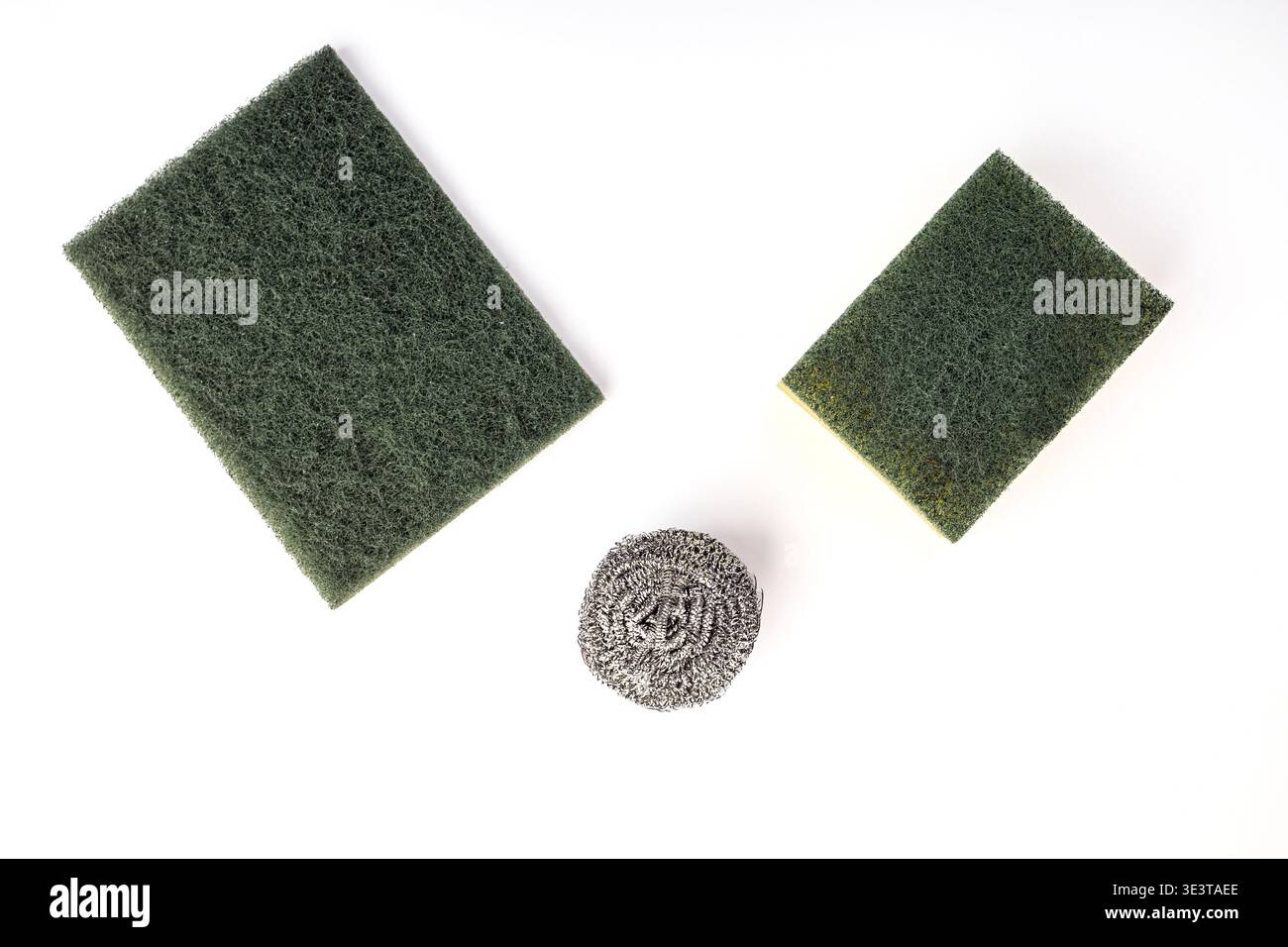 Posa piatta di tre comuni utensili per lavastoviglie e lavastoviglie su una superficie bianca. Include un grande tampone abrasivo in nylon verde, un du verde e giallo Foto Stock