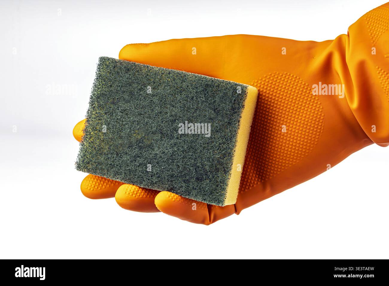 Primo piano di una mano che indossa un guanto in gomma arancione per la pulizia della casa che afferra una spugna rettangolare a due lati con una S abrasiva verde Foto Stock