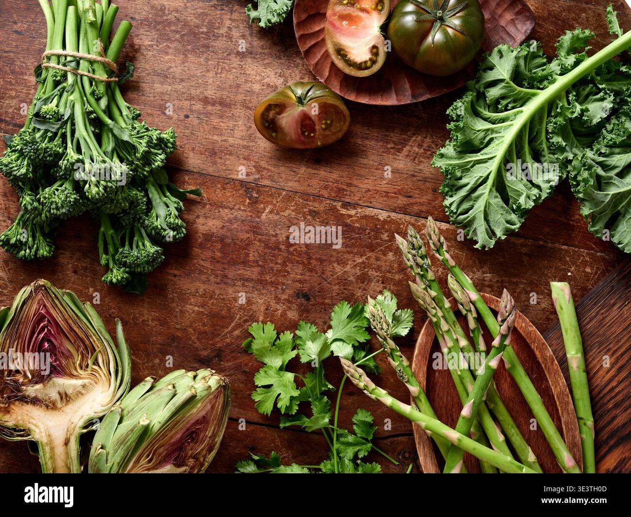 Le verdure fresche sono disposte su una superficie rustica in legno. La selezione comprende verdure e pomodori. Questa configurazione mostra l'idea di creare un sano Foto Stock