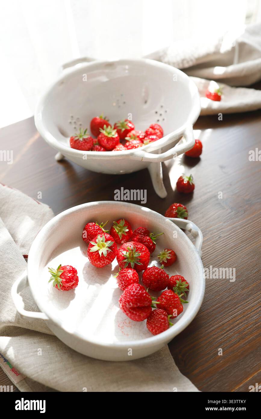Fragole rosse fresche in una ciotola vintage in ceramica bianca su un tavolo di legno scuro. La fotografia estetica del cibo mostra i frutti di bosco estivi biologici per una vita lenta Foto Stock