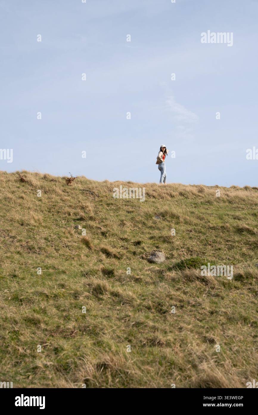 Donna in piedi sulla cresta collinare di Coniston contro il cielo blu, Lake District, Cumbria, Inghilterra Foto Stock