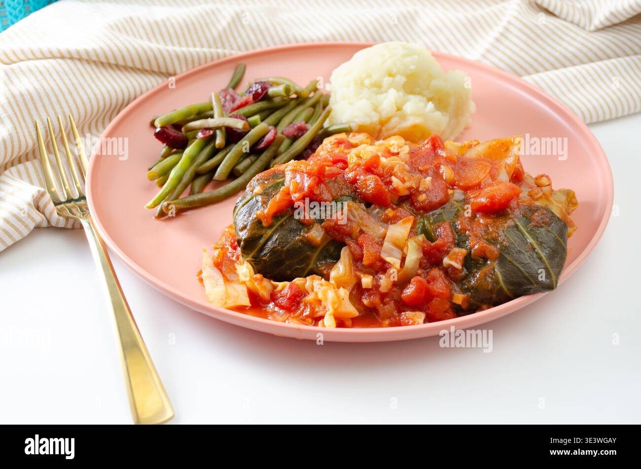 Un delizioso pasto con involtini di cavolo con una ricca salsa di pomodoro, servito insieme a una porzione di crema di patate e fagiolini freschi con cra Foto Stock