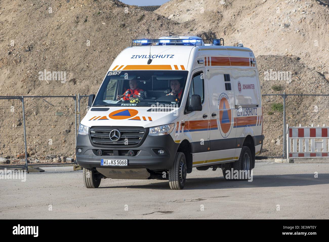 Un'ambulanza della difesa civile è parcheggiata in un cantiere vicino a mucchi di sabbia e recinzioni di barriera Foto Stock