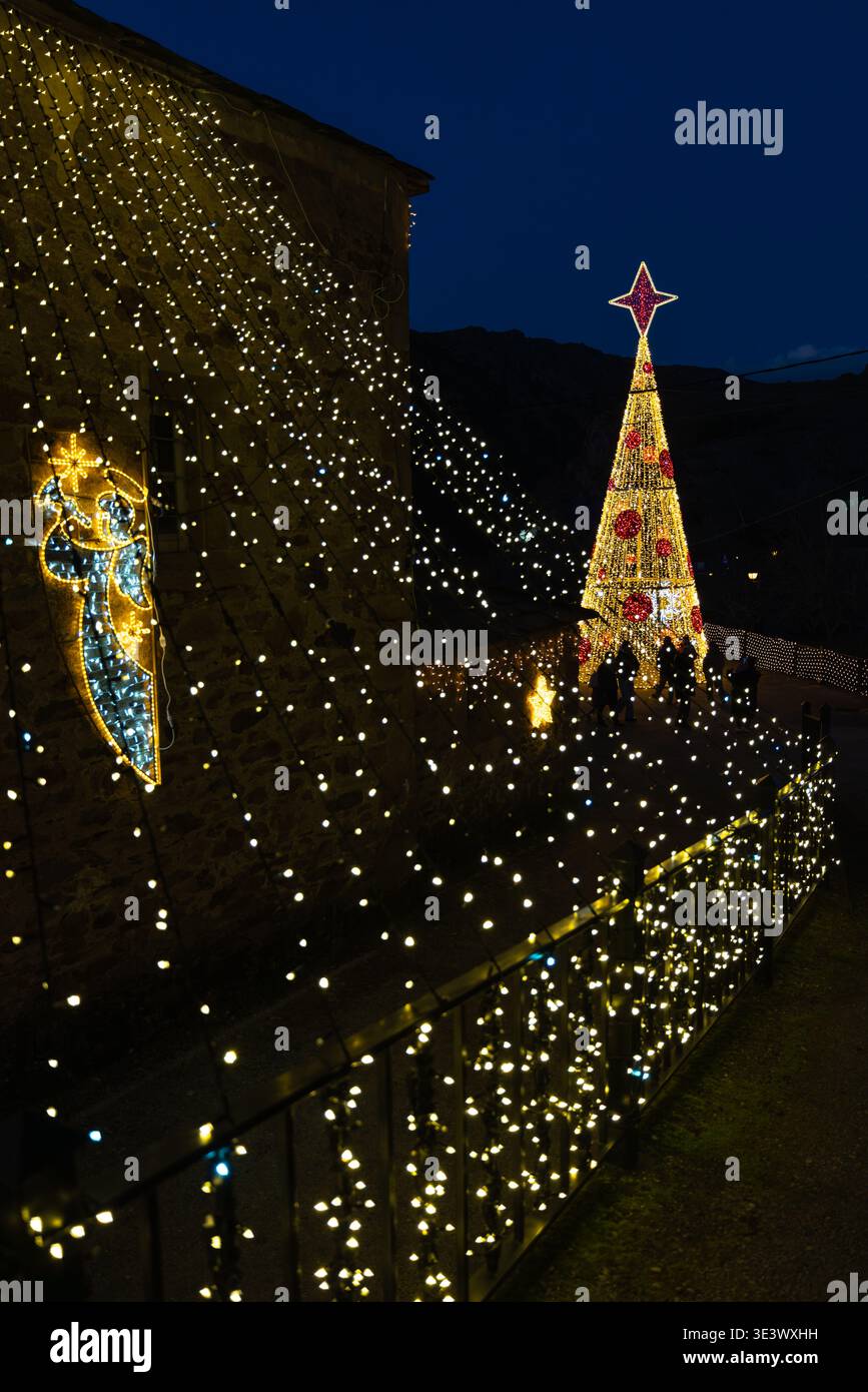 Accogliente scena notturna invernale con luci festose che illuminano il villaggio. Foto Stock