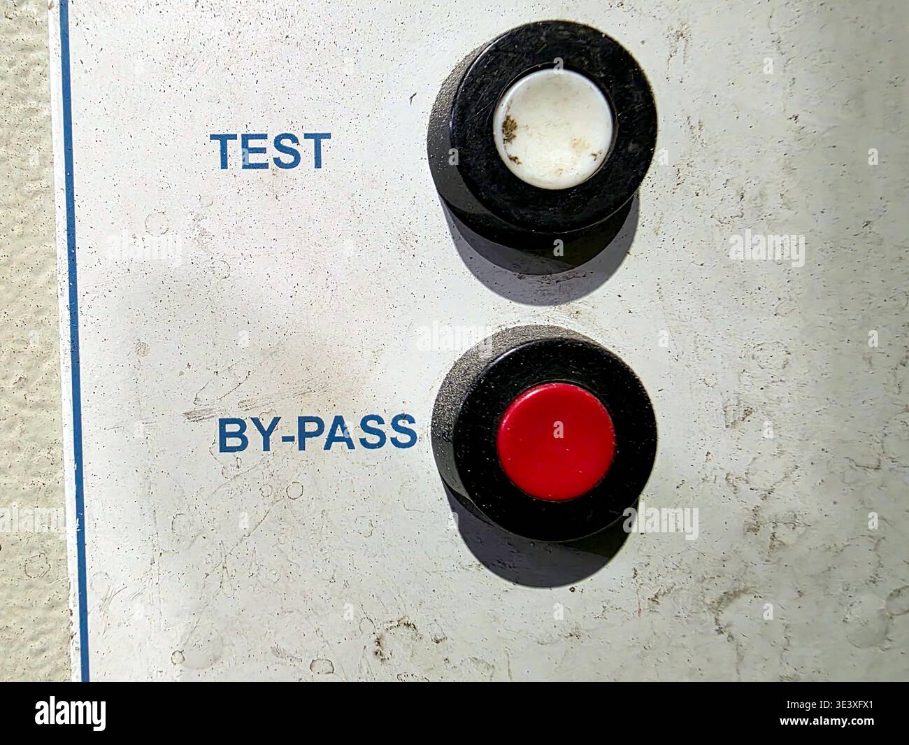 Sul pannello di controllo vengono visualizzati due pulsanti, uno per il test e l'altro per il bypass. Il pannello si trova in una sala di controllo e mostra un po' di usura. Foto Stock