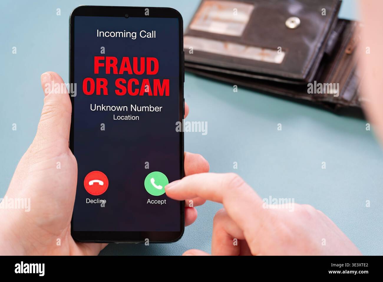 Primo piano dello smartphone con lo smartphone in mano e sullo schermo viene visualizzato un avviso di truffa in arrivo, che sottolinea il tentativo di frode, la consapevolezza delle minacce informatiche, la sicurezza mobile, lo scavo Foto Stock