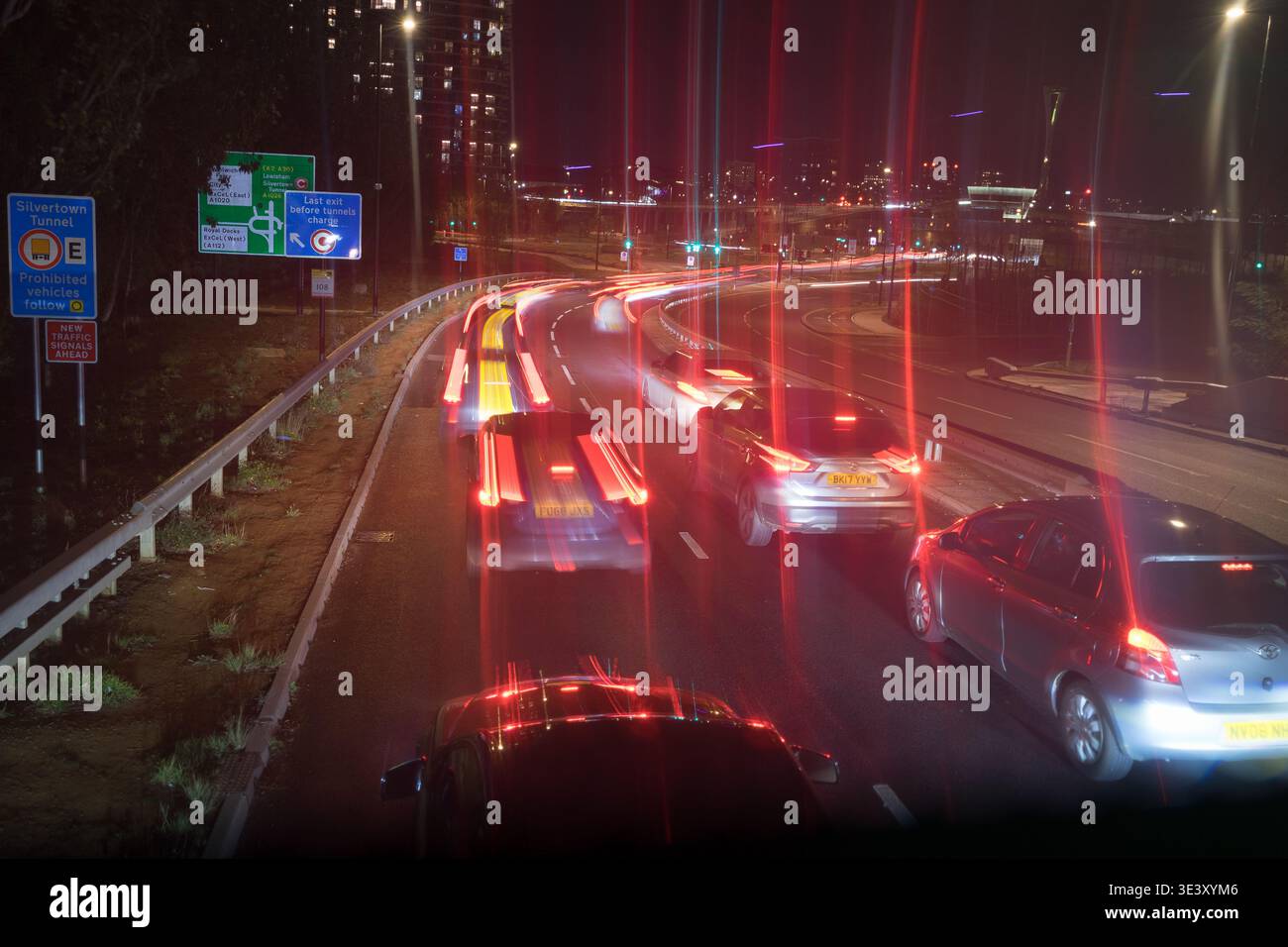 Traffico notturno al portale Newham Silvertown Tunnel, Londra. Lunga esposizione per catturare tracce di luce e segnaletica per la zona di pedaggio istituzionale Foto Stock
