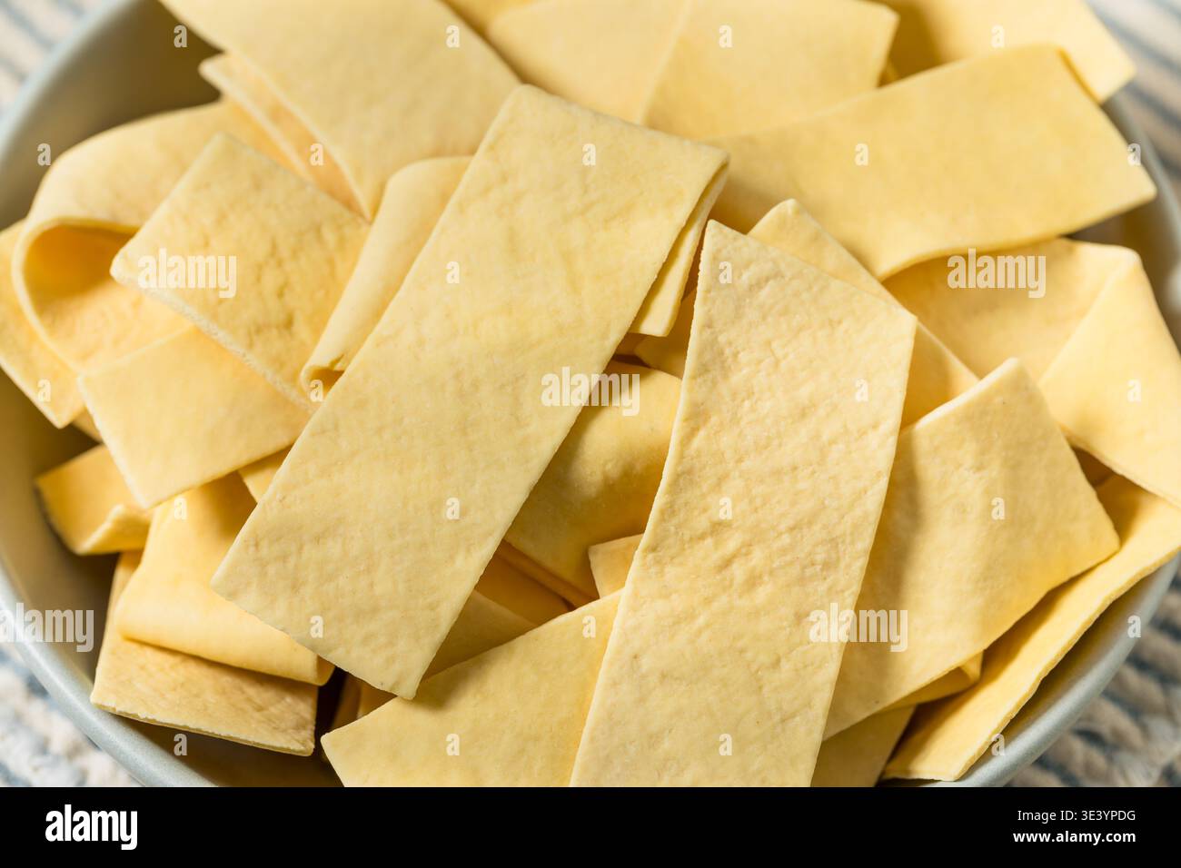 Asciugare gli spaghetti organici larghi in una ciotola per cuocere la zuppa Foto Stock