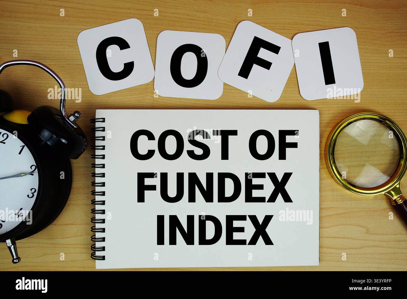 Testo COFI Cost of Fundex Index scritto su blocco note con lente d'ingrandimento e sveglia su sfondo in legno Foto Stock