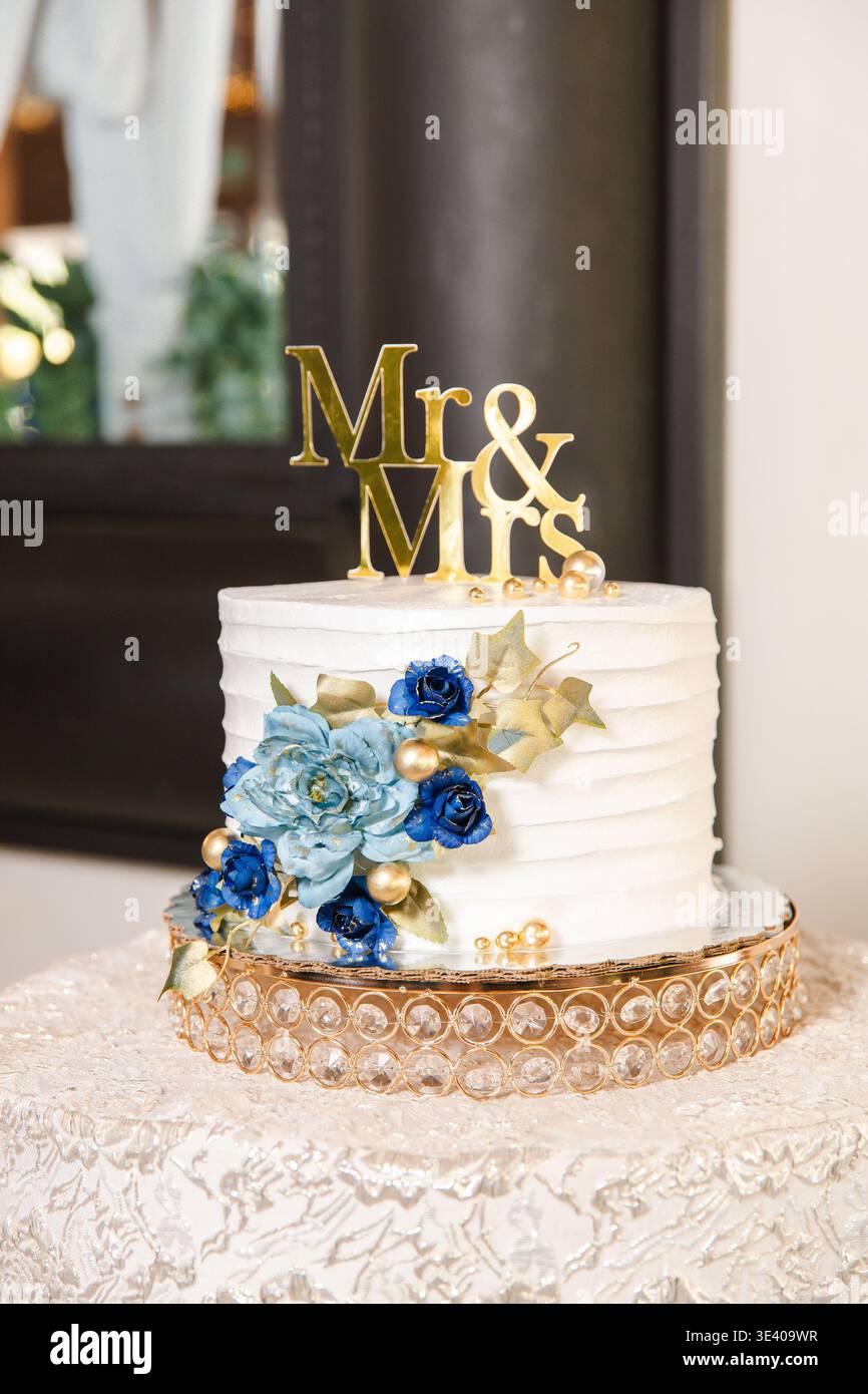 Elegante torta nuziale con topper "Mr & Mrs" e decorazioni floreali. Foto Stock