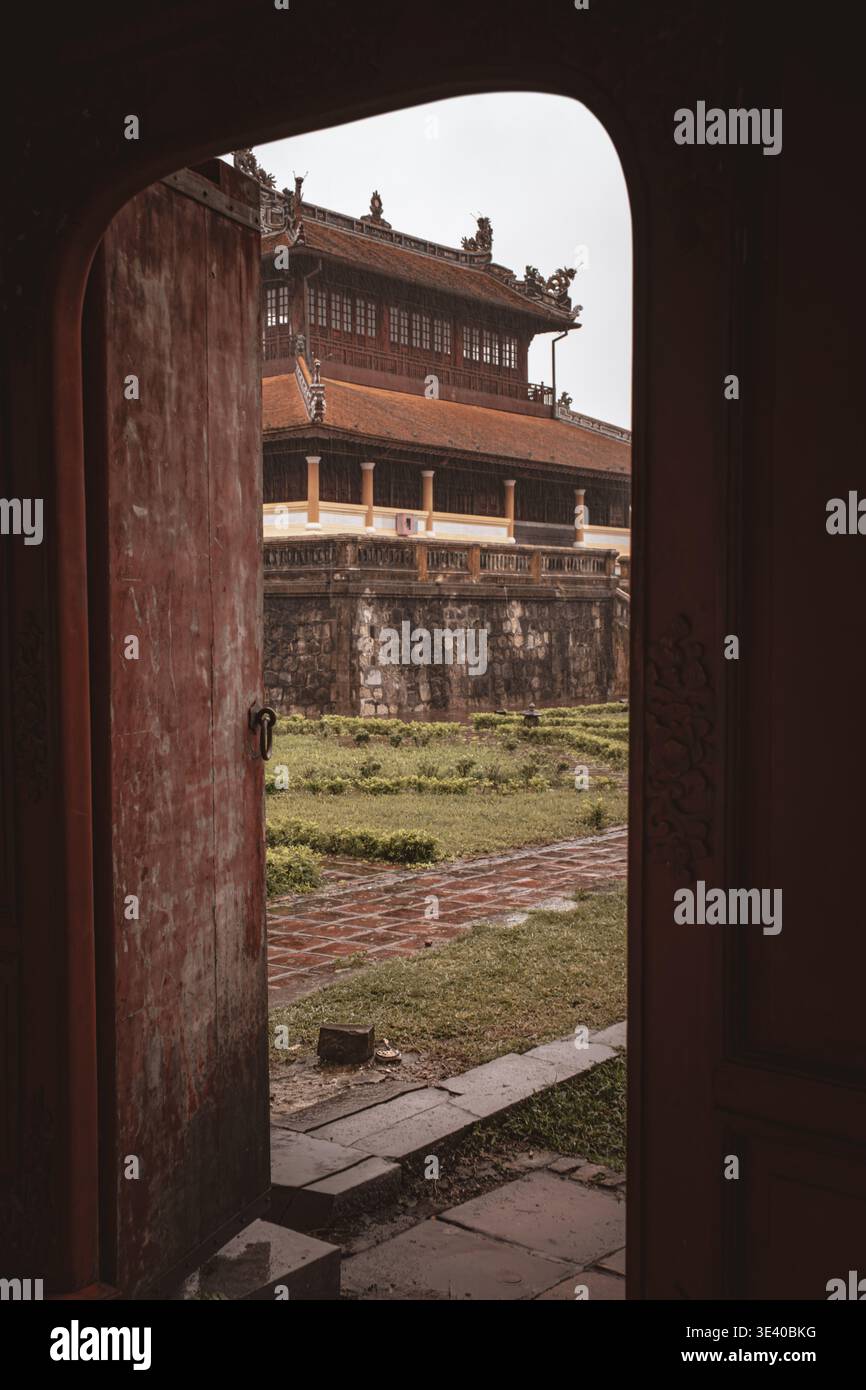 Sala imperiale ornata con tetto piastrellato incorniciato da una porta aperta ad arco rossa, Hue Imperial City, Vietnam. Foto Stock