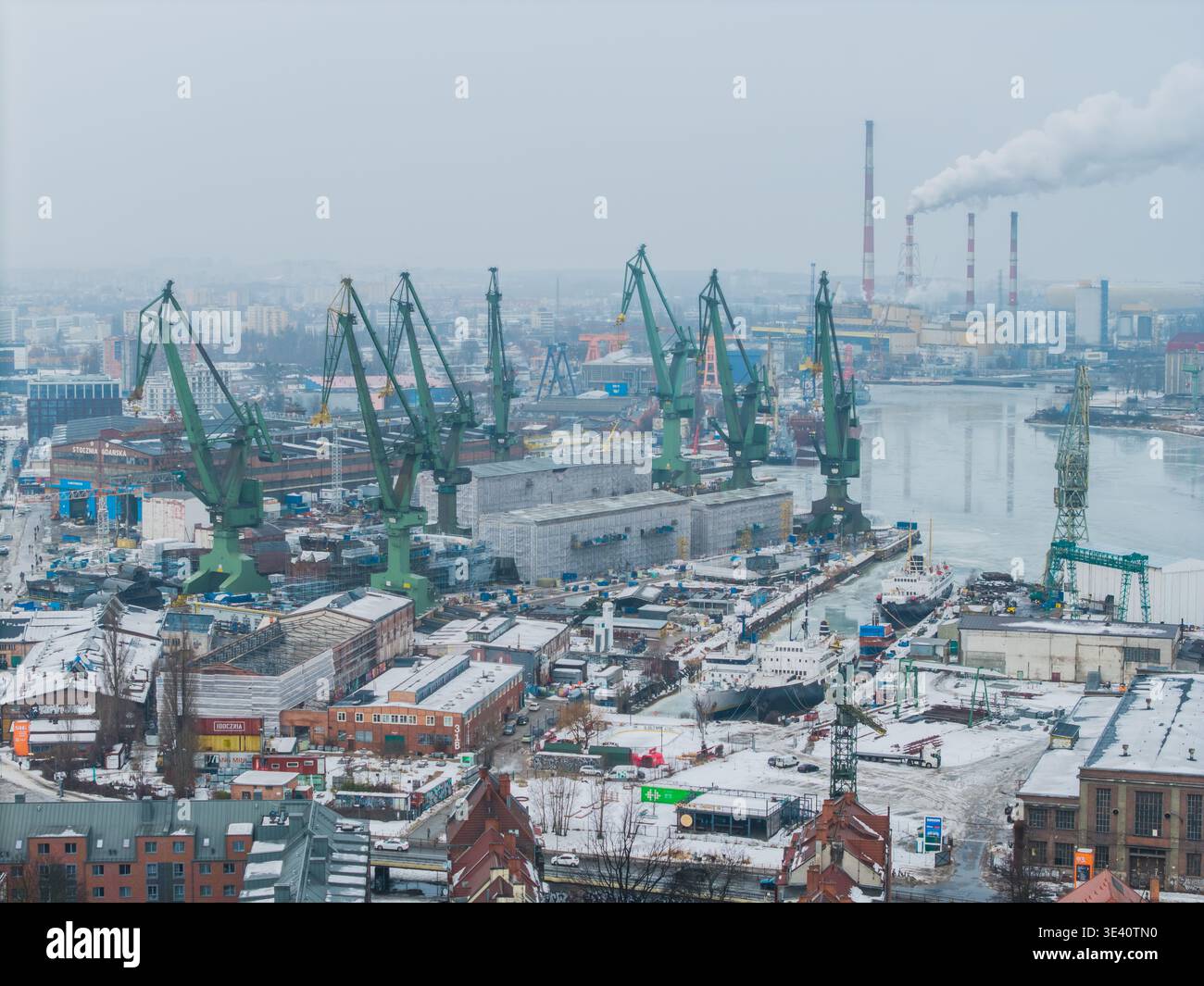 Veduta aerea di imponenti gru che si trovano a sentinella sul cantiere navale, una sinfonia di acciaio e industria contro il freddo e grigio cielo, Danzica, Polonia. Foto Stock