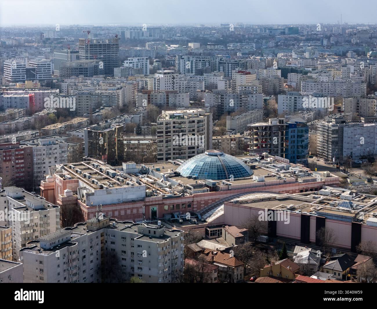 Veduta aerea di un vasto paesaggio urbano con una prominente struttura a cupola di vetro in mezzo a un mare di edifici, Bucarest, Romania. Foto Stock