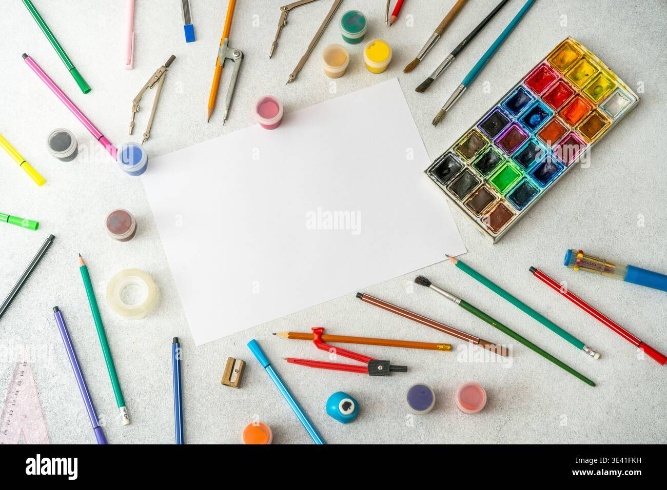 Scrivania Creative Art Workspace con foglio bianco vuoto, pallet colorato ad acquerello, matite, pennelli e strumenti di disegno. Vista dall'alto dello sfondo dello studio scolastico Foto Stock