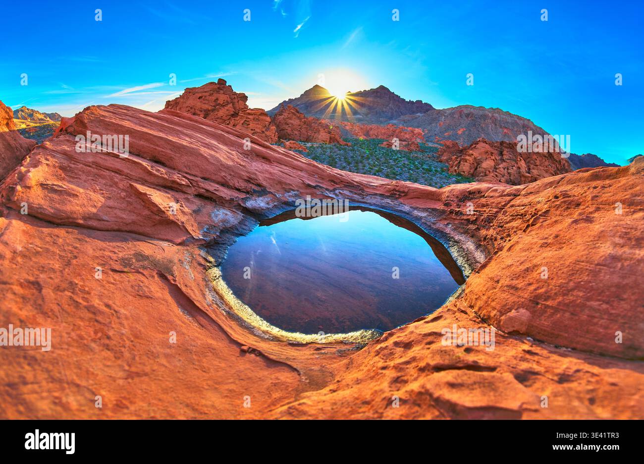 Redstone Dune Desert Tinaja con Sunrise Sunburst e Water Reflection in Nevada Foto Stock