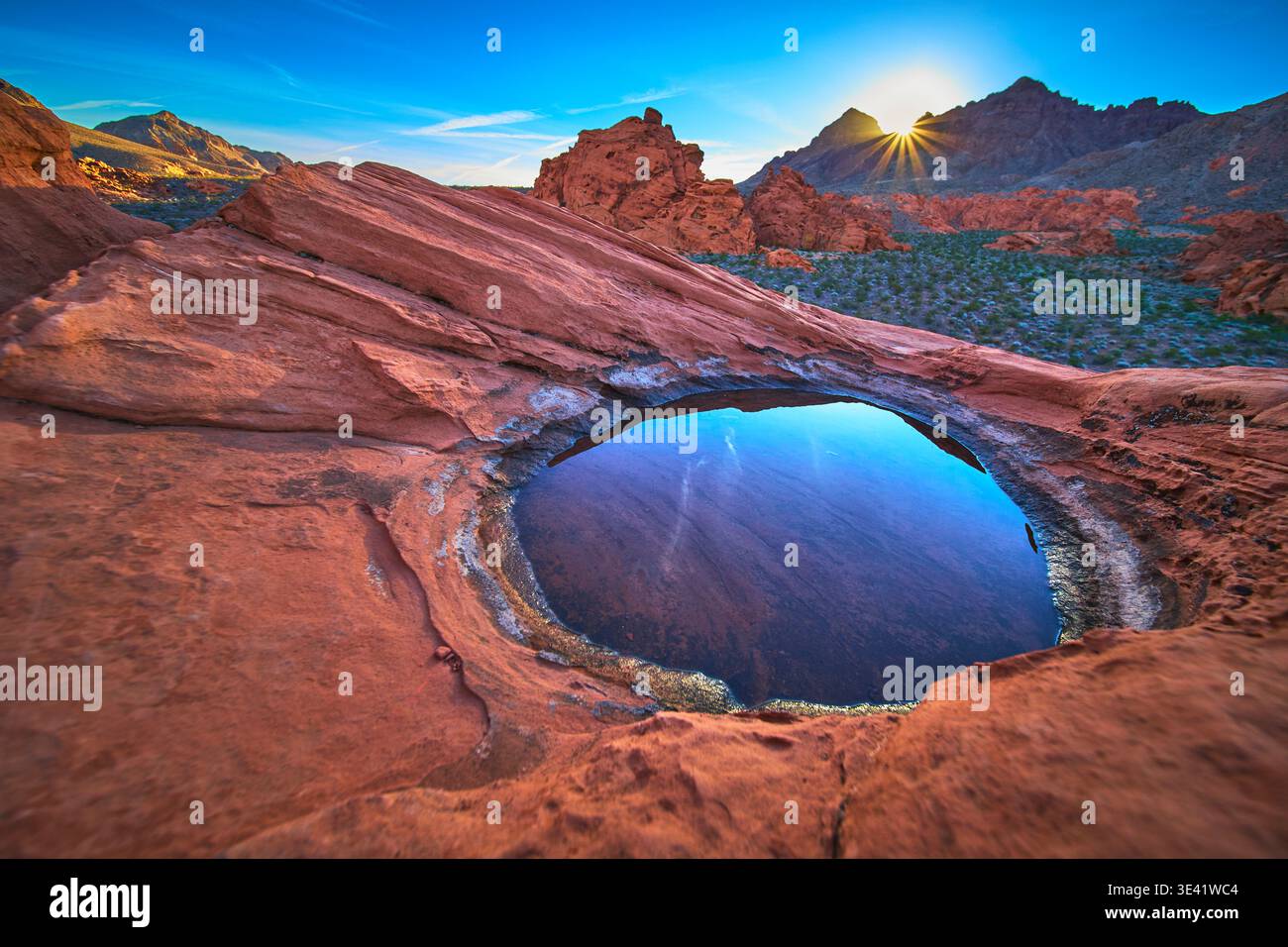 Alba sulle dune di Redstone con riflessione sull'acqua Desert Tinaja e Sunburst nel vibrante Nevada Foto Stock
