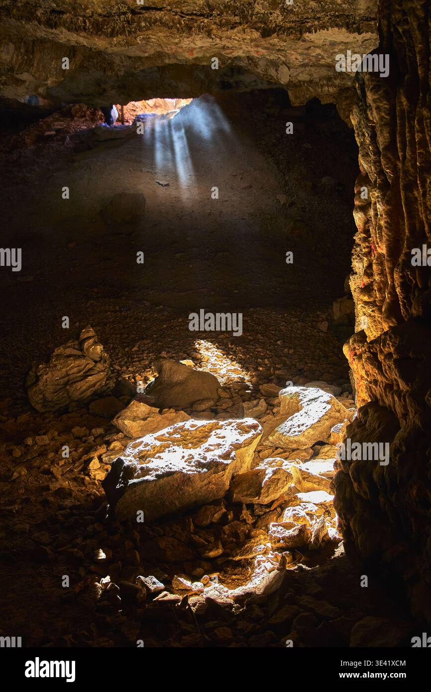 Interno della grotta con rocce illuminanti a raggi di sole e ombre spettacolari Foto Stock