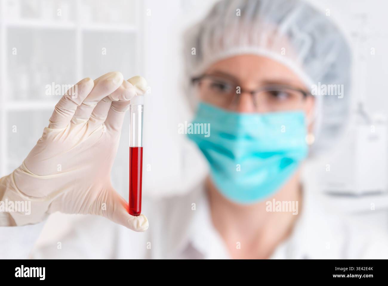 Professionista di laboratorio specializzato che esamina il campione di liquido rosso in provette per analisi, diagnostica clinica e ambiente di ricerca scientifica Foto Stock