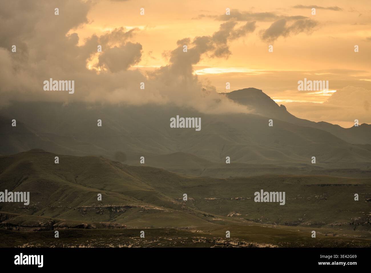 Picchi distanti e pendenze erbose ondulate. Tranquilla scena rurale con Hazy Mountains e Cloud Cover Foto Stock