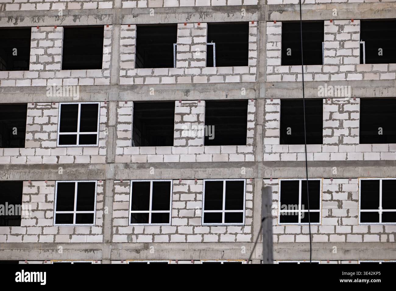 Edificio in costruzione con blocchi di cemento e nuove finestre sulla facciata dell'appartamento Foto Stock