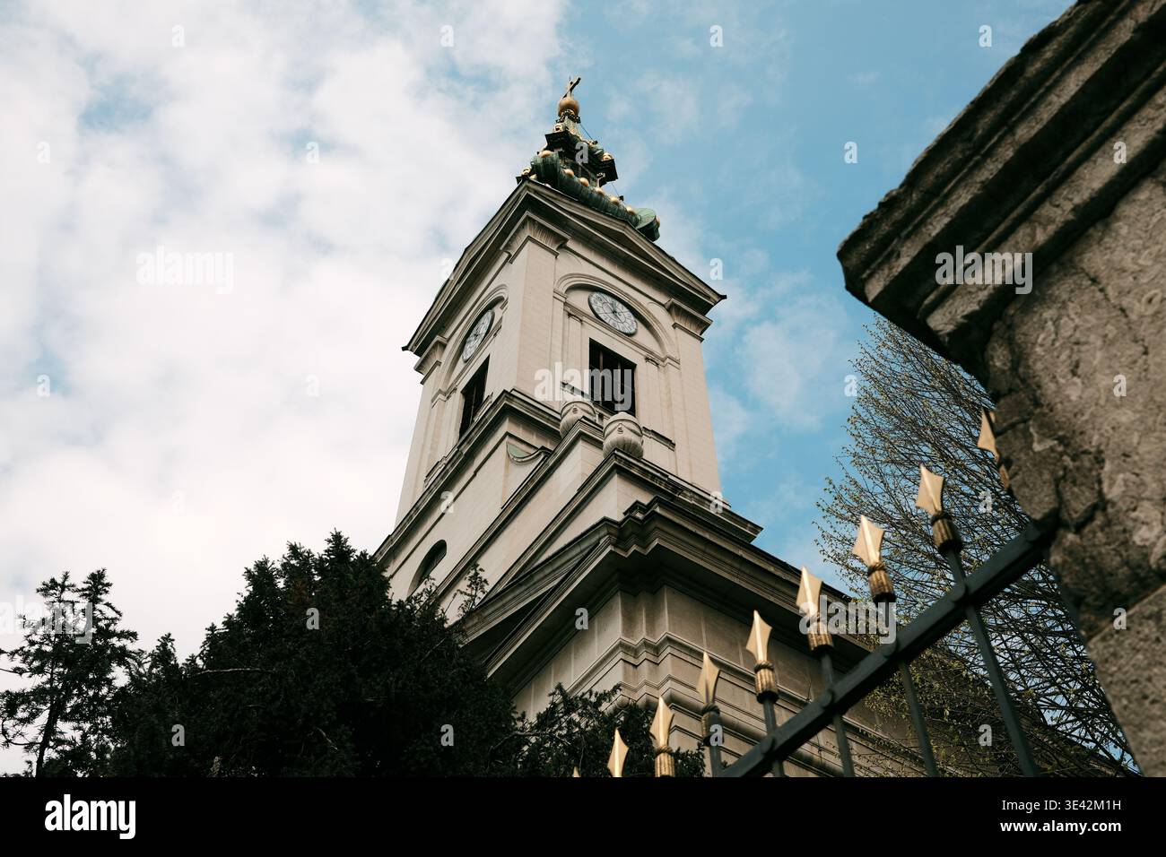 Torre della chiesa ortodossa con orologio e croce circondata da edifici cittadini a Belgrado. Concetto di tempo, tradizione e patrimonio culturale. Foto Stock