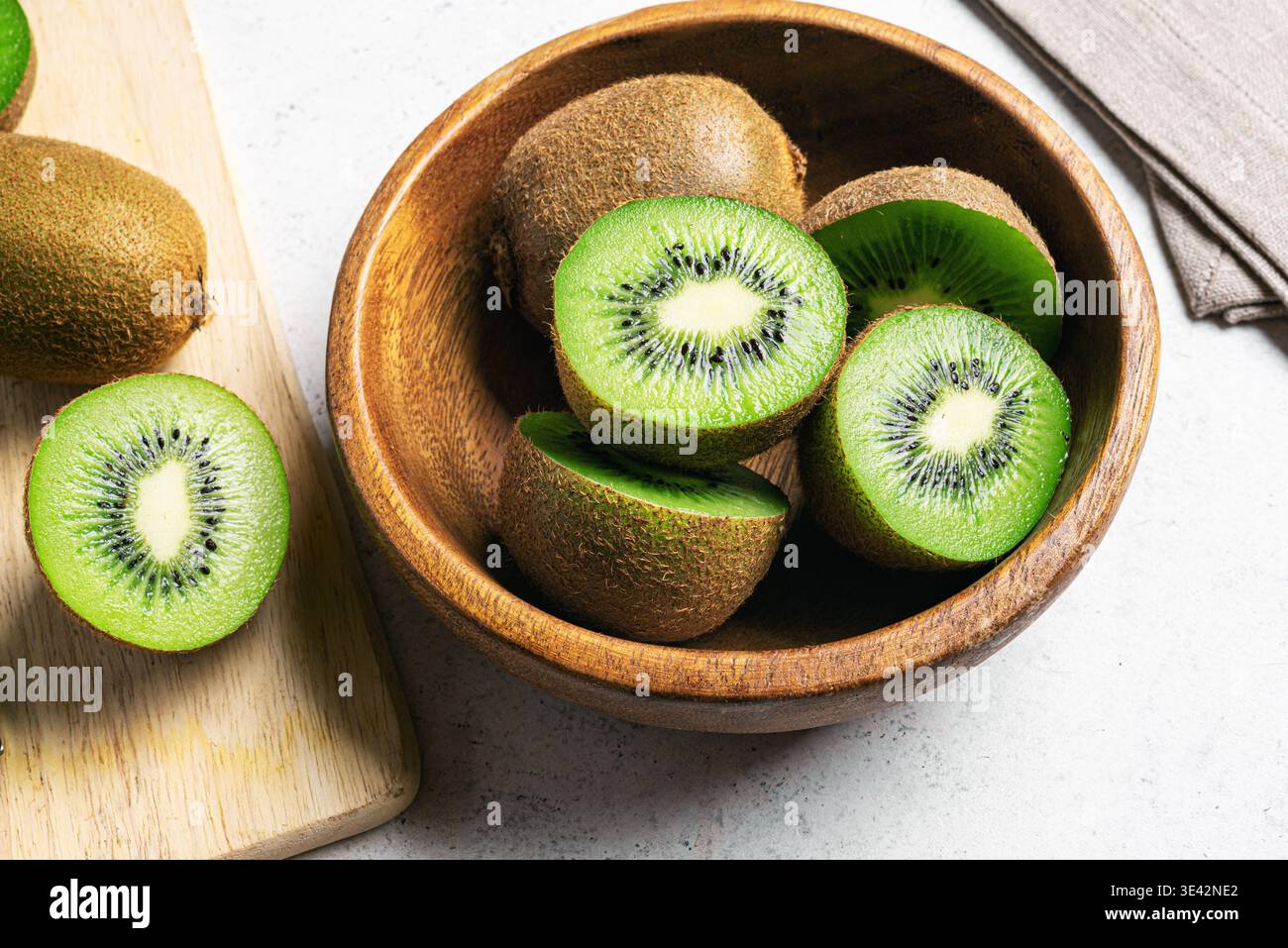 Frutta kiwi su sfondo di legno. Frutta intera e mezzo pezzetti di kiwi verde nel recipiente. Kiwi fresco e maturo. Frutta tropicale. Frutta biologica. Mangiare sano Foto Stock