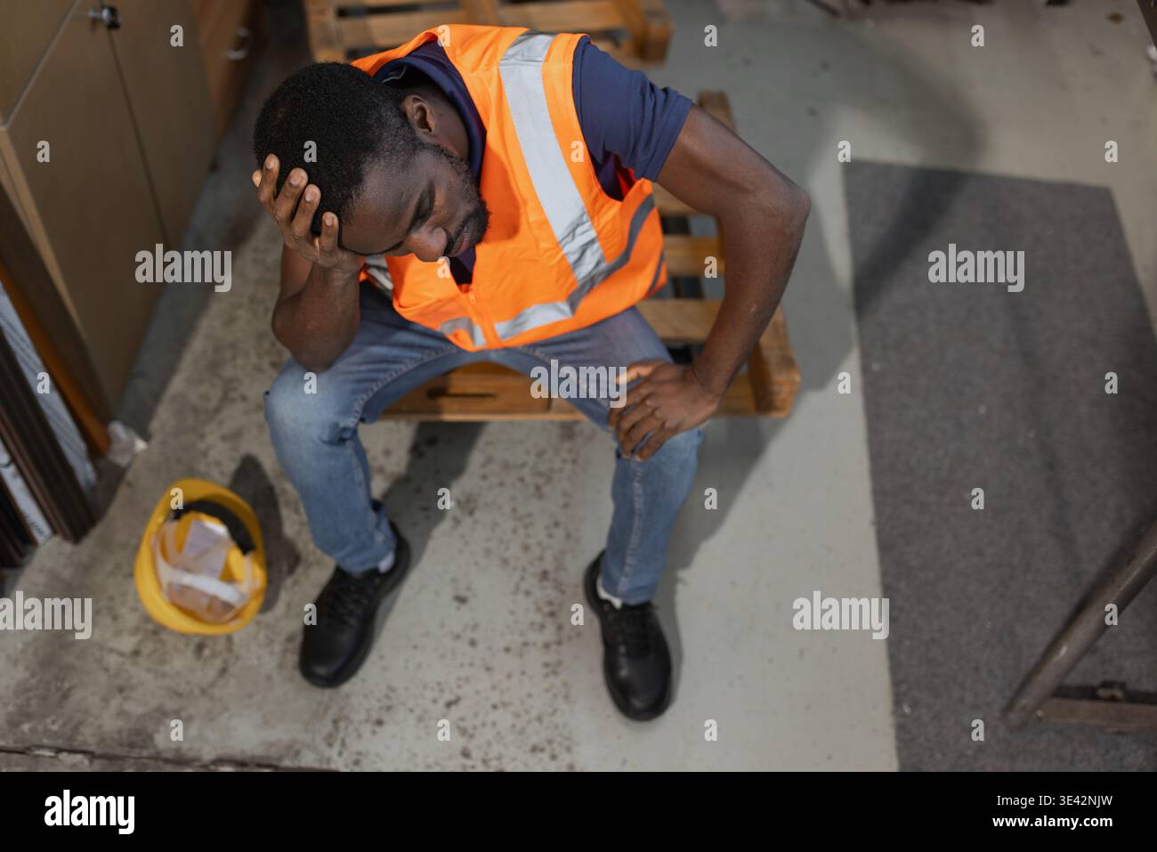 I lavoratori afroamericani si sentono sopraffatti e stanchi, si prendono una pausa dallo stress estremo del lavoro e dall'esaurimento in un magazzino di stoccaggio industriale. Foto Stock