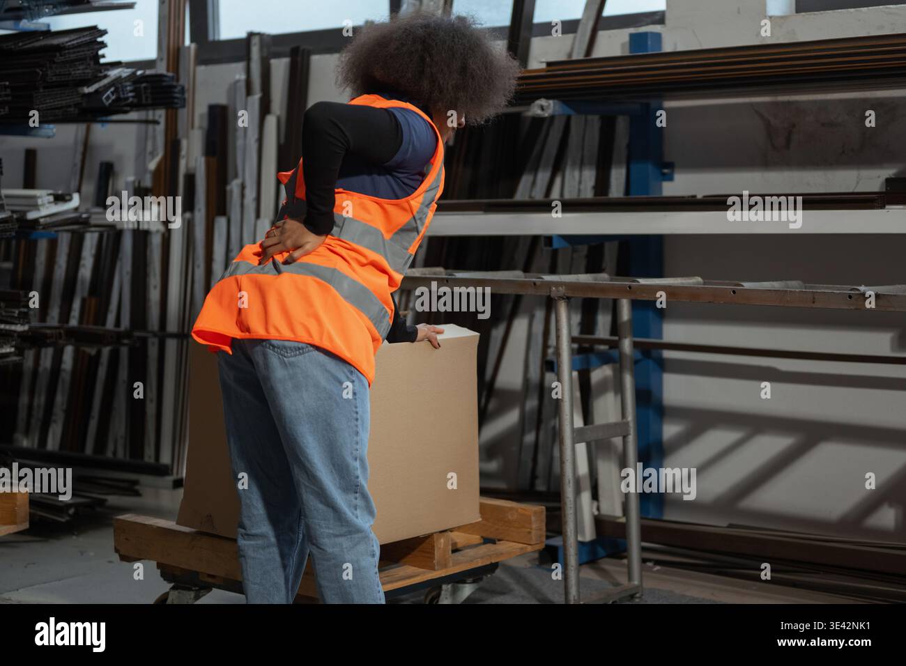 Donna addetto alla logistica e al magazzino che soffre di mal di schiena dopo la movimentazione manuale, il sollevamento e il trasporto di pesanti scatole di cartone. Foto Stock
