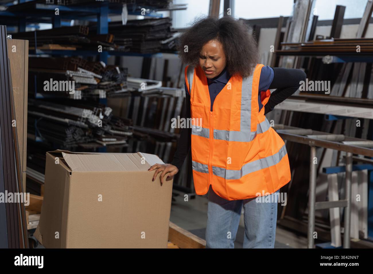 Donna addetto alla logistica e al magazzino che soffre di mal di schiena dopo la movimentazione manuale, il sollevamento e il trasporto di pesanti scatole di cartone. Foto Stock
