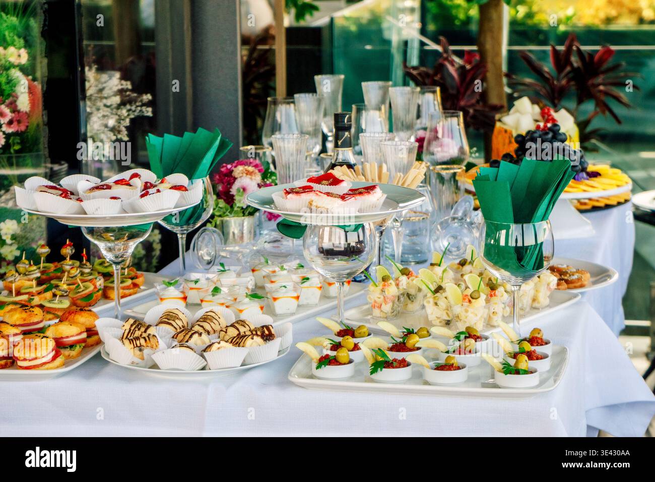 Dessert e bicchieri da vino su elegante tavolo con quadrati di cioccolato, frutta, cornici e morbide. Foto Stock
