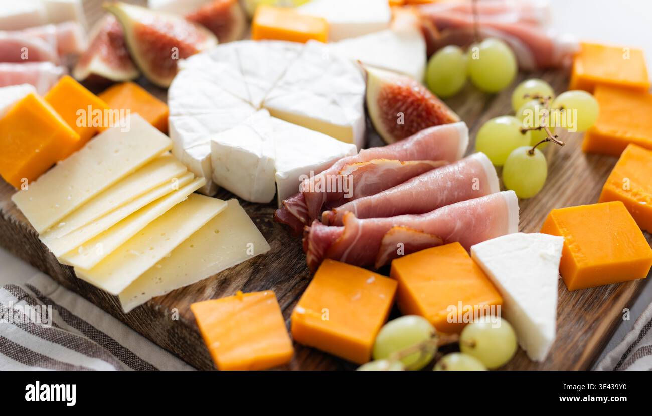 Tagliere di formaggi con frutta e prosciutto su Un tavolo come antipasto per Una festa Foto Stock