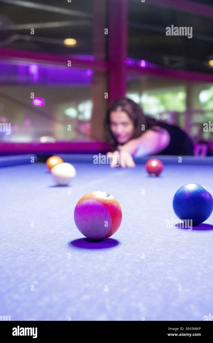 Un giocatore concentrato si sta preparando a scattare un colpo impressionante in un vivace tavolo da biliardo con palline colorate Foto Stock