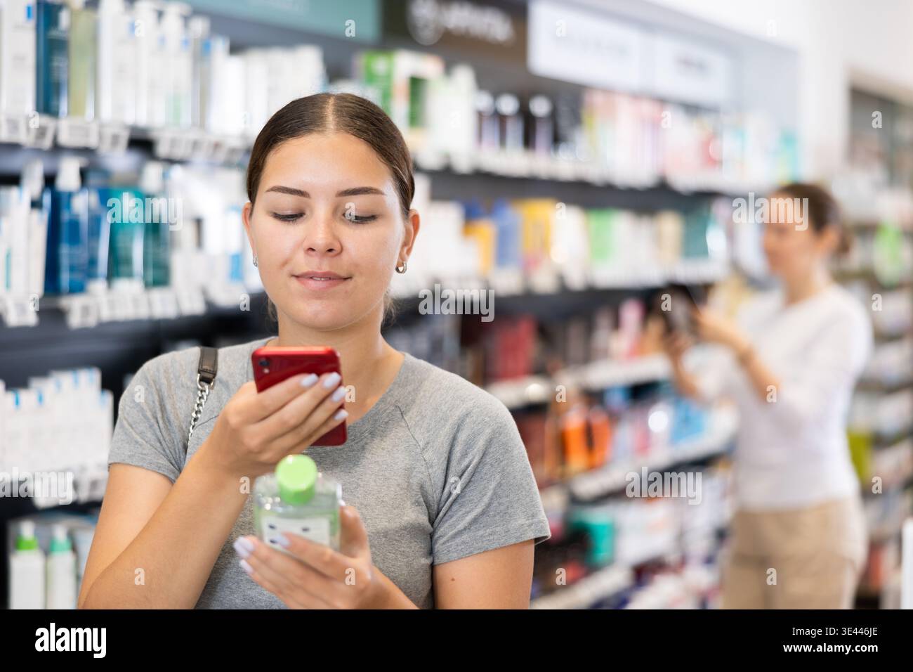 Donna acquirente scansione di un codice a barre su una confezione di cosmetici con il suo telefono. Ricerca di informazioni tramite Internet Foto Stock