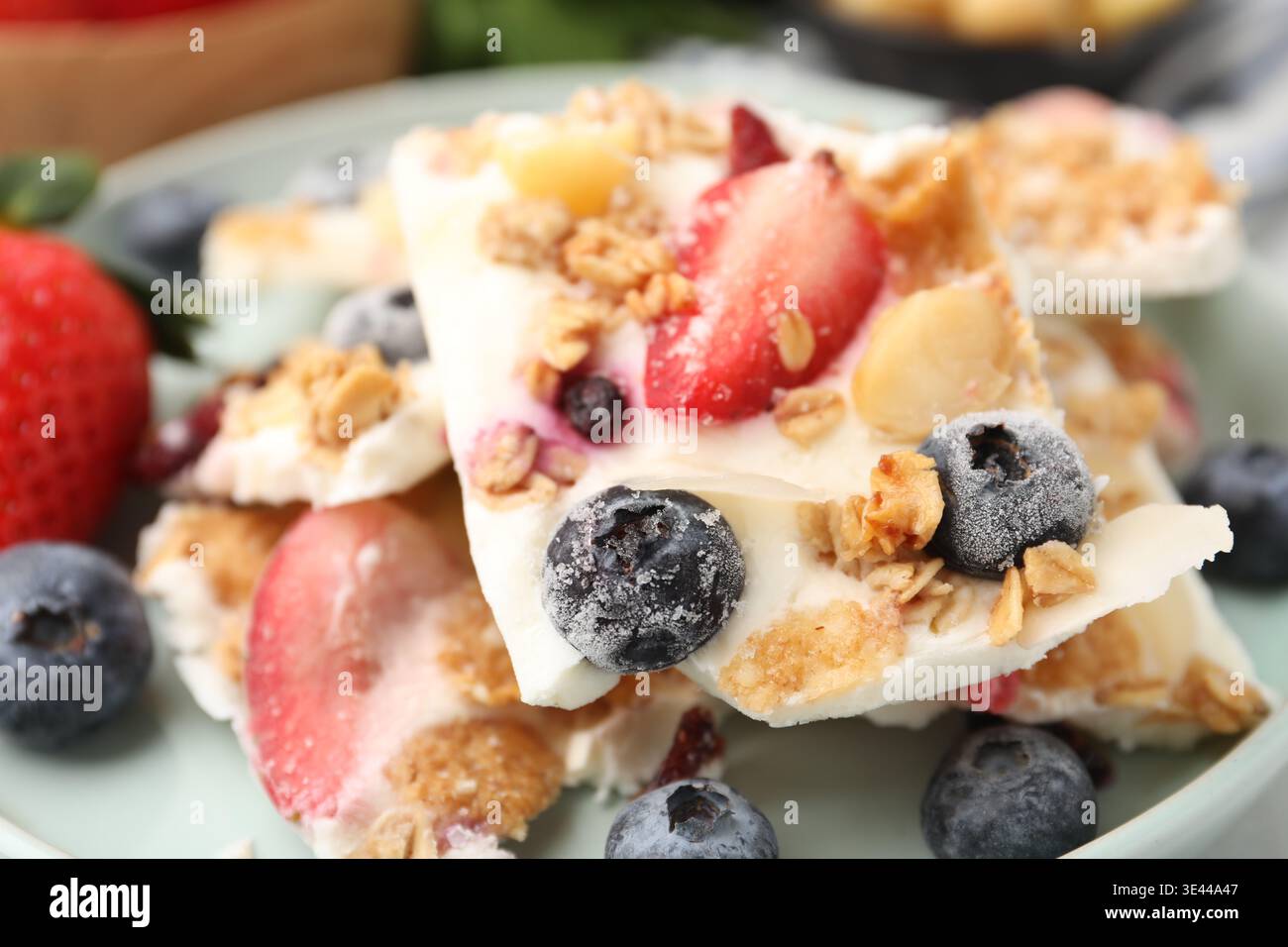 Pezzi di gustosa corteccia di yogurt con frutti di bosco e muesli sul tavolo, primo piano Foto Stock
