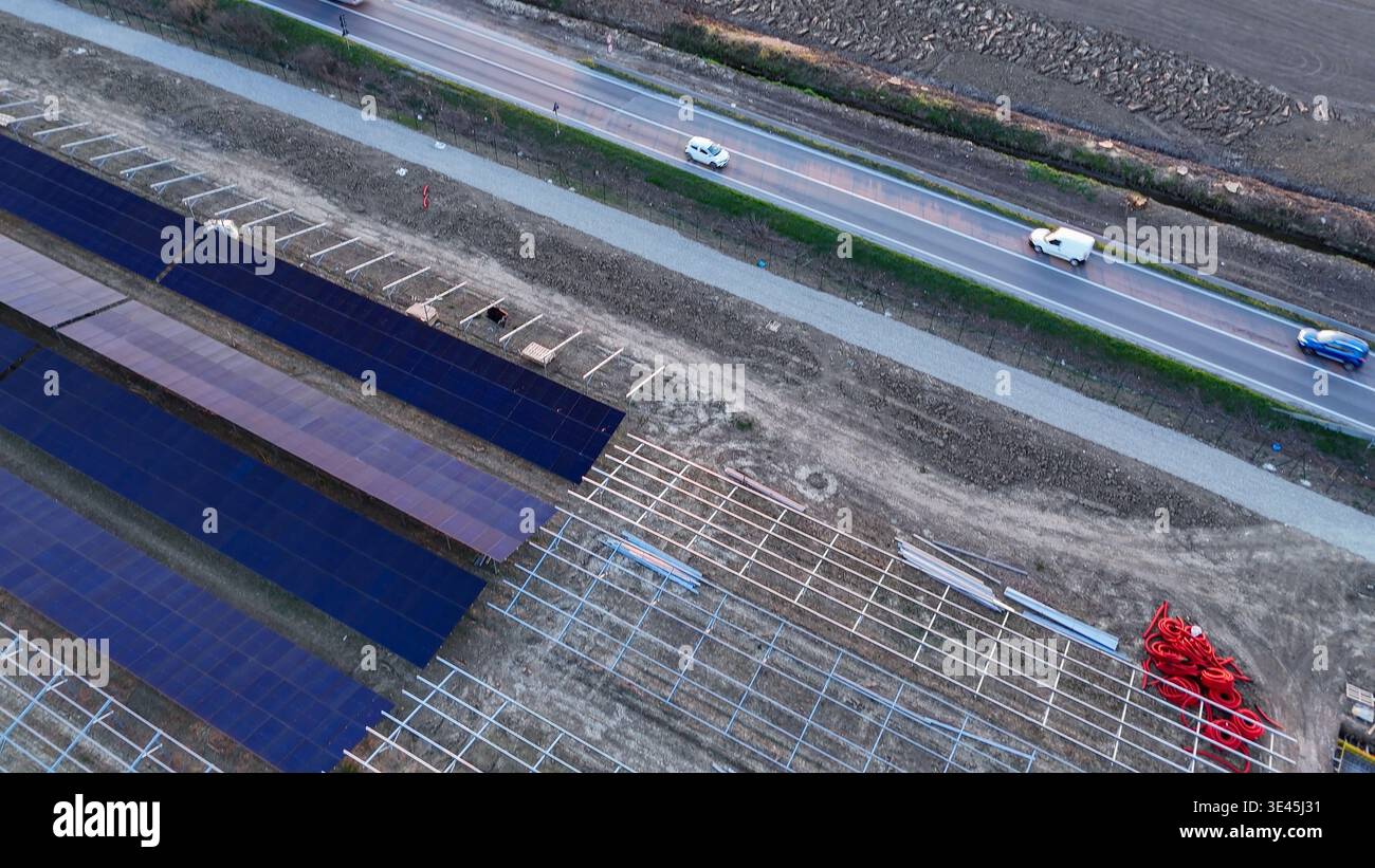 Impianto solare in costruzione su campi agricoli, con file di pannelli fotovoltaici e strutture di montaggio, che rappresentano lo sviluppo sostenibile A. Foto Stock