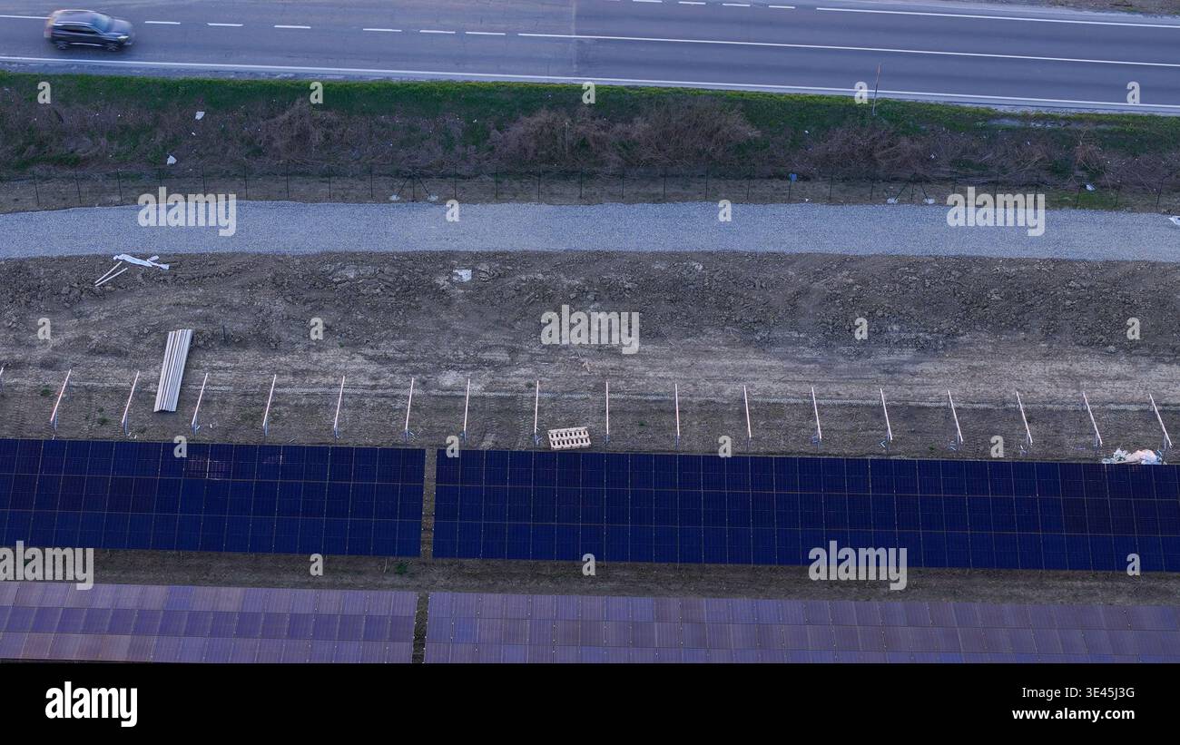 I pannelli solari vengono installati durante la costruzione di un impianto fotovoltaico in una zona agricola, generando energia pulita e promuovendo la sostenibilità Foto Stock