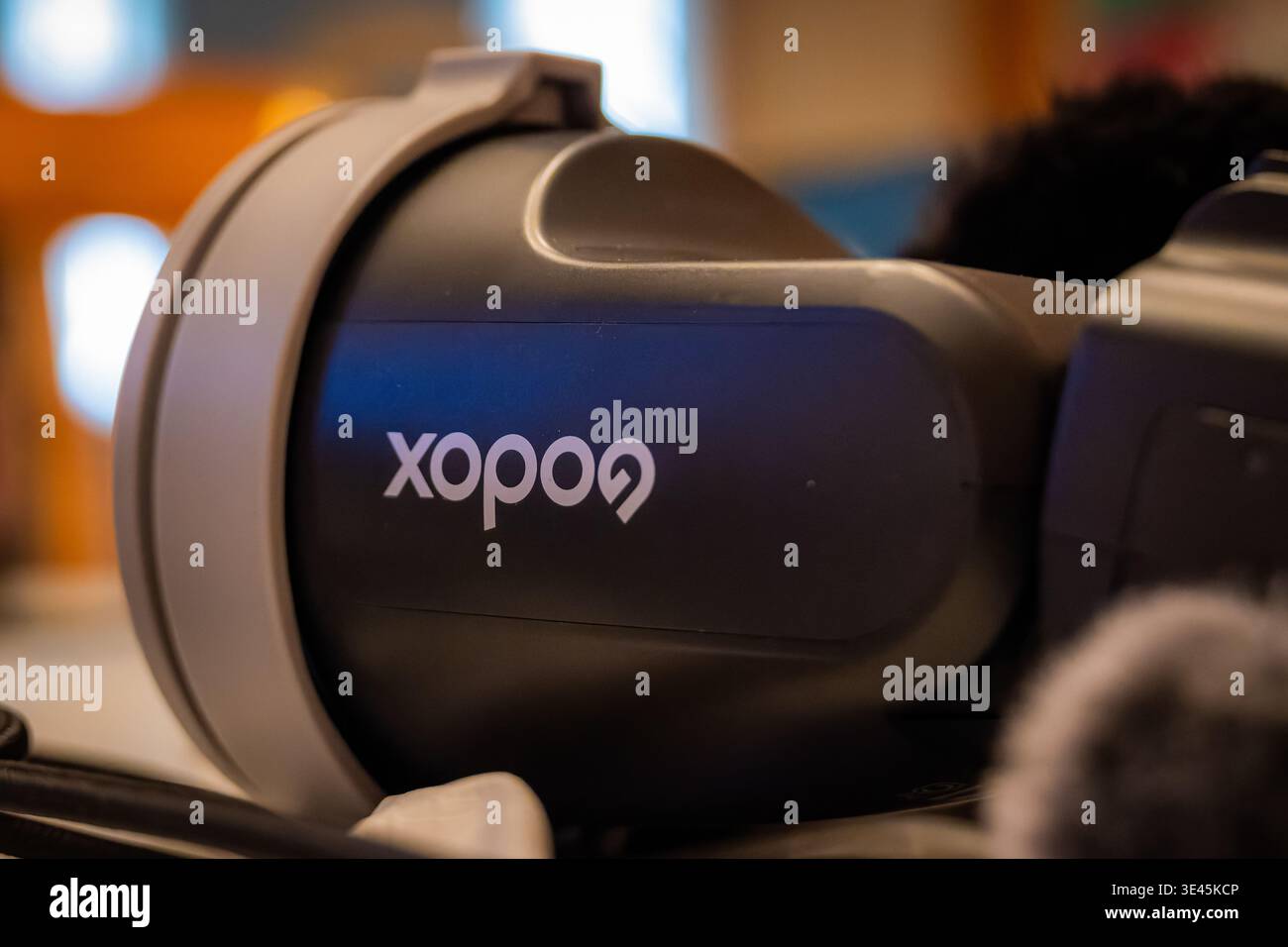 Una vista macro di un'unità flash stroboscopica portatile Godox serie ad incentrata sul logo del marchio con una profondità di campo ridotta in un ambiente interno Foto Stock