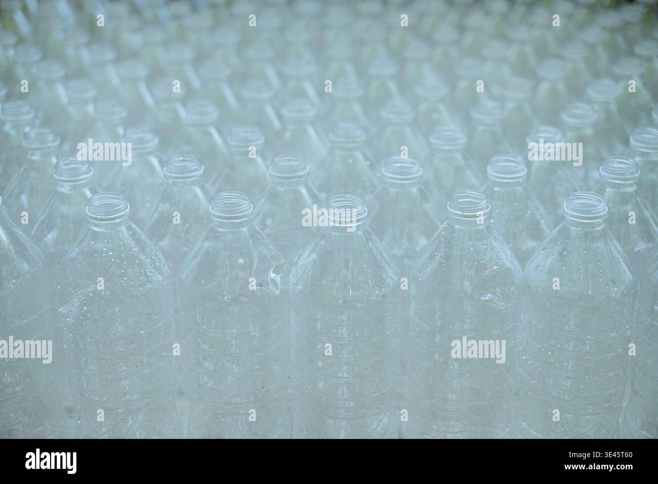 Diversi flaconi di plastica trasparente vuoti senza tappi sono stati impilati in fila. Foto Stock