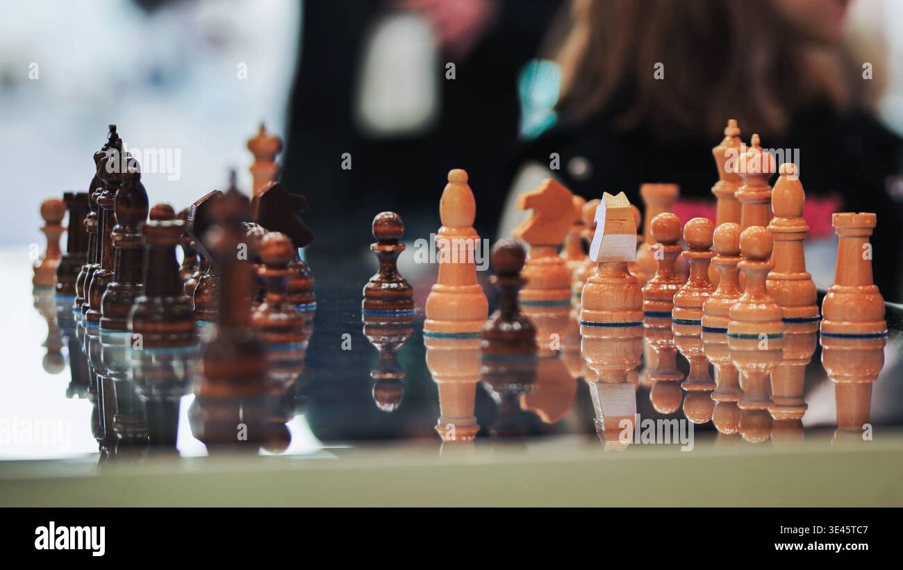 Pezzi di scacchi pronti per la strategia e la competizione su una tavola riflettente Foto Stock